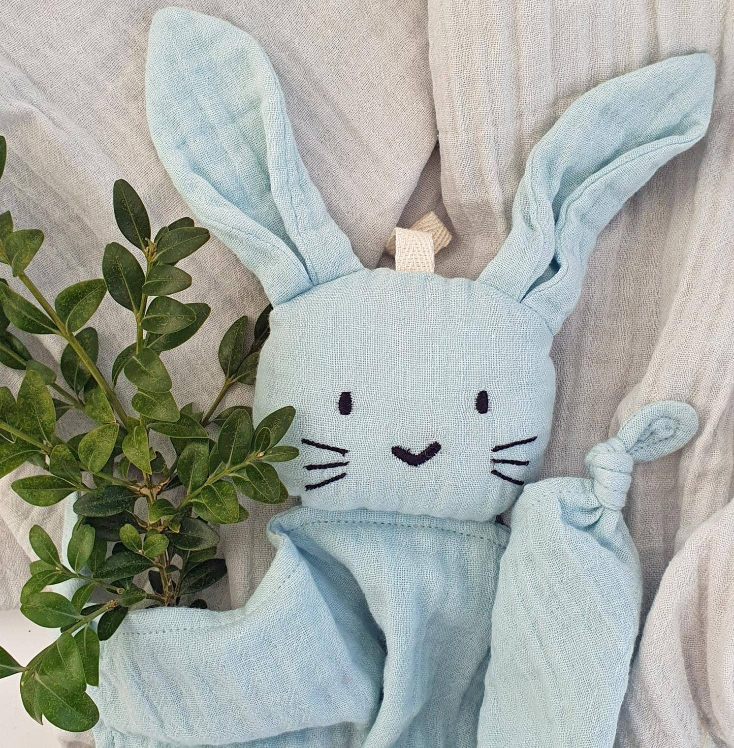 Doudou lapin bleu zoomé au niveau de la tête. On y voit ses petits yeux, son nez et ses moustaches noirs.