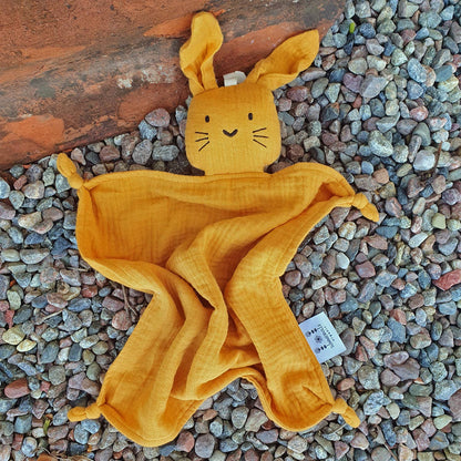 Doudou lapin orange couché sur les graviers