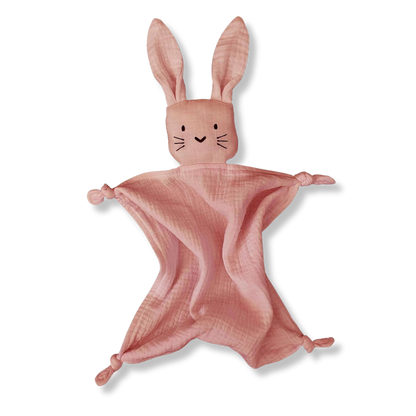 Doudou pour bébé en forme de lapin, en coton bio rose, avec de longues oreilles et des petits noeuds au niveau des pattes. Il a de petits yeux noirs ainsi que des moustaches noires et un petit nez en forme de coeur noir.